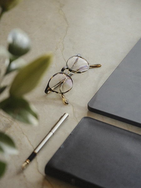 Óculos, caneta e notebook sobre a mesa em ambiente de psicoterapia.